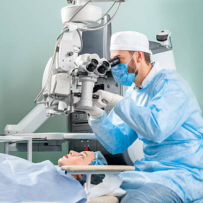 Surgeon looking into the microscope at the eye of female patient at the operating room